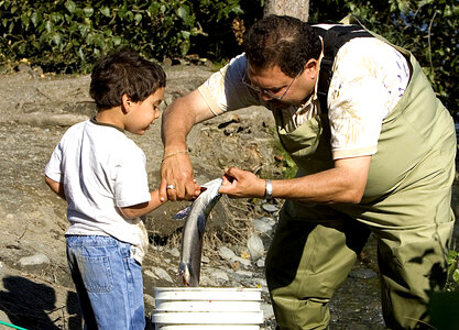Fisherman teaches a child about fish handling photo
