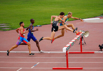 Male sprinter leaping over hurdles photo