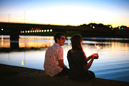 Couple of Young People Sitting on the Dock Against a Blurred Background photo