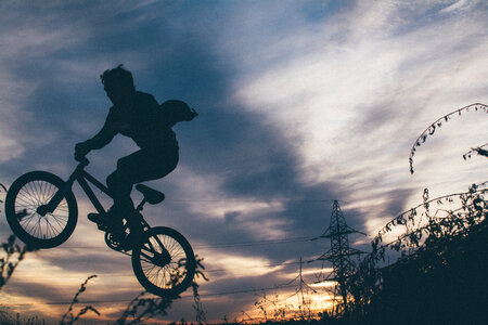 Silhouette of a Young Man Jumping on a Bike photo