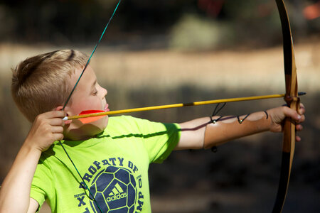 Child drawing a bow and arrow photo