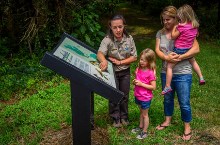 FWS Visitor services staffer shows interpretive panel to family