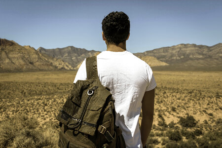 Young Man Alone with a Travel Backpack in a Desert photo