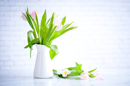 Vase with Bouquet of Tulips on Brick Wall Background photo