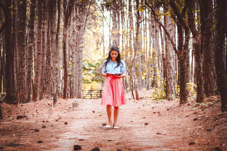 Cute Brunette Walking and Reading Book in the Forest photo