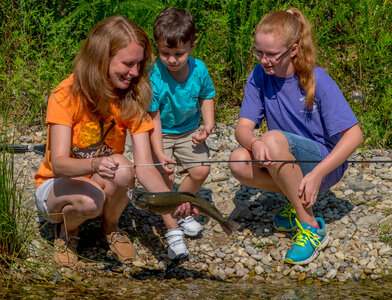 Family fishing, mother nets rainbow trout-1 photo