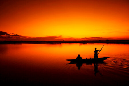 silhouette of fishermen with yellow and orange sun in the backgro photo