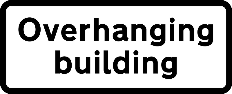 Supplementary plate informing height limit warning is of an overhanging building