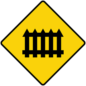 Level railroad crossing with barriers ahead sign in Liberia