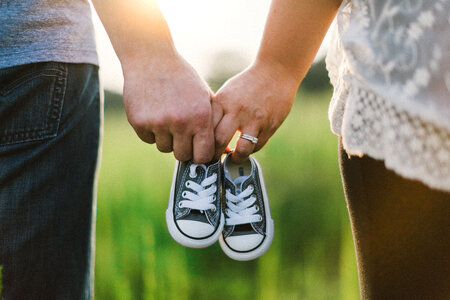 Future Parents Holding Hands and a Pair of Little Baby Shoes photo