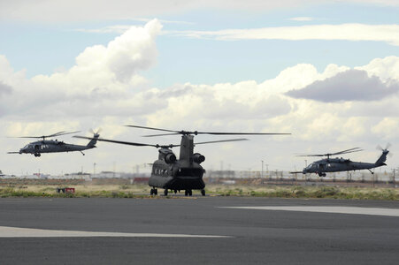 Two HH-60G Pave Hawks take off as a CH-47 taxis photo
