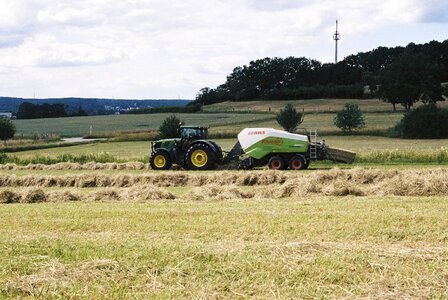 Farmers harvesting hay by tractores in sunny day. photo