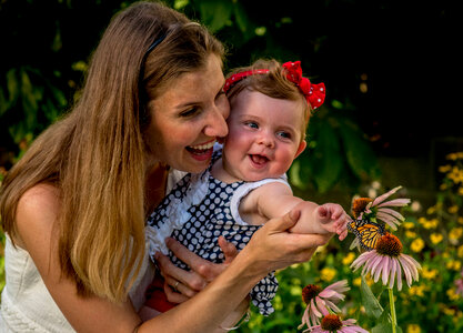Mother and daughter observe monarch on flower