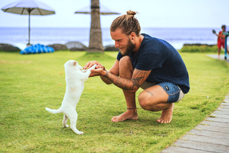 Bearded Guy Holding Little White Puppy Outdoors photo