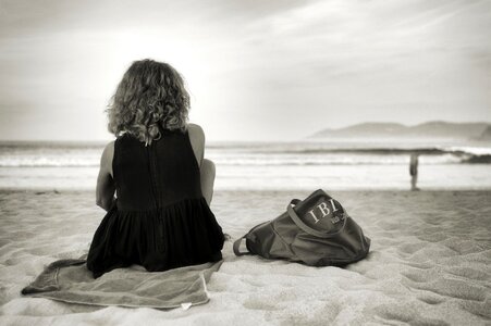 A young slim woman seated on a black sand beach photo
