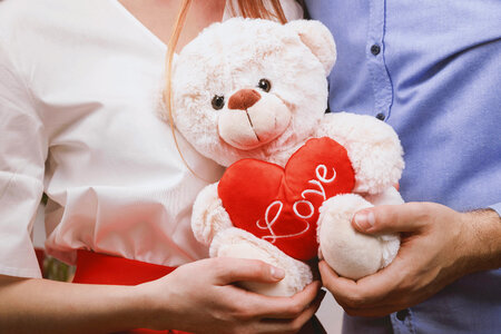 Young couple holding toy teddy bear and celebrating Valentine’s Day