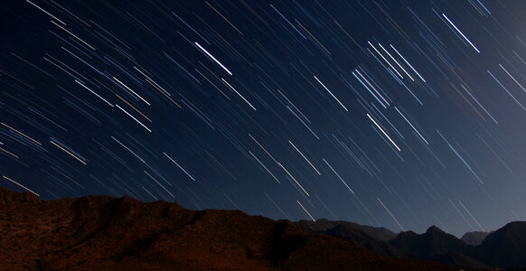 Star trails over the mountains in night sky photo