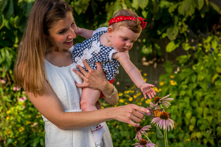 Mother and daughter look at monarch on flower-1