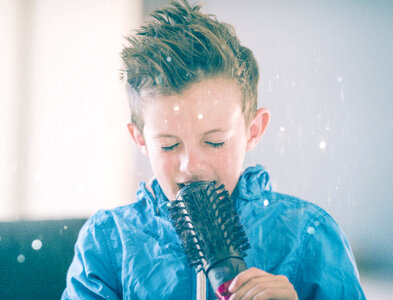 Little Boy Singing Using a Hairbrush as Microphone photo