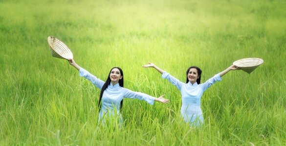 Two young women smiling and raising hands up on sunris background