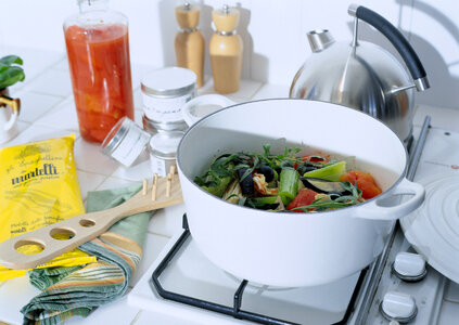 Stock pot on a stove with vegetables cut for making soup