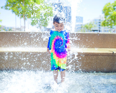 Smiling Boy is Bathed and Splashing in the Fountain photo