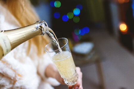 Young girl pours champagne into a glass photo