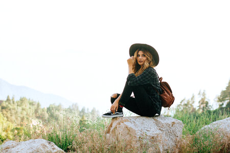 Woman with Backpack Sitting on the Rock photo