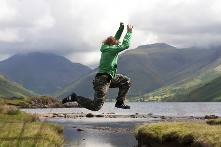 Young Boy Jumping Over the Mountains Lake Water photo