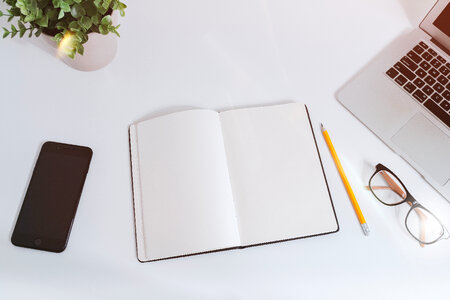 White work table with notes, smartphone and laptop