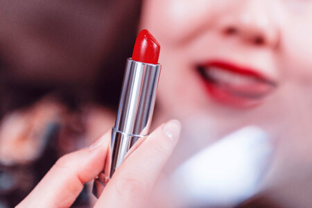 Beautiful woman applying red lipstick photo
