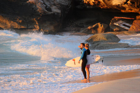 Young couple walking on beach with surfboards in arm photo