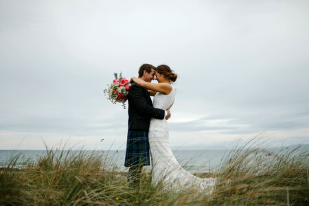 Happy and Lovely Wedding Couple Cuddling on the Beach photo