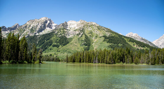 Mountains landscape across the lake with green water photo