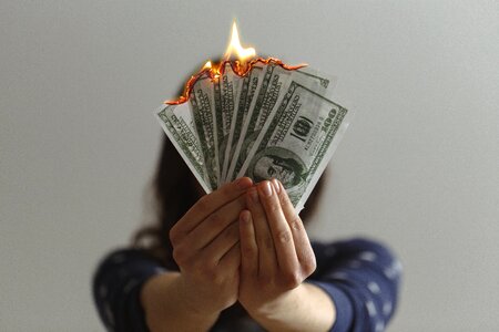 Hand Holding Bills on Fire photo