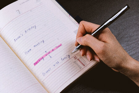 2 The woman’s hand holds a pencil and writes a plan into a diary at home