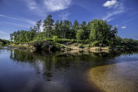 Trees and landscape across the river under sky and clouds