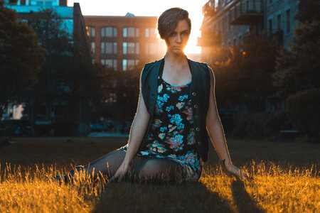 Young Pretty Woman Sitting on the Grass at Sunset photo