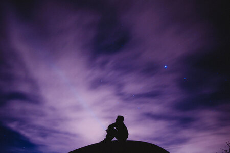 Silhouette of Sitting Man on a Hill Watching the Night Sky photo