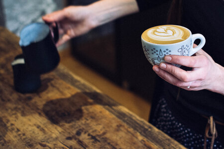 Barista holding a cup with coffee cappuccino photo