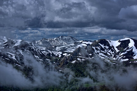 Clouds over the snowy mountain tops photo