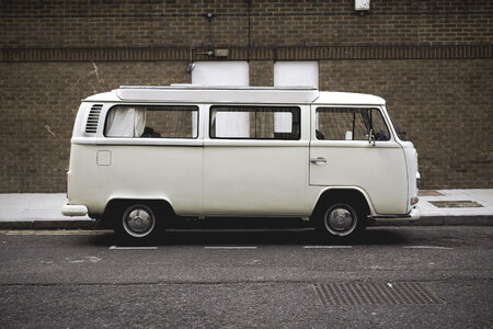 A White Volkswagen Minibus Parked in Front of Brick Wall photo