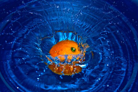 Orange in water splashes on a black blue photo