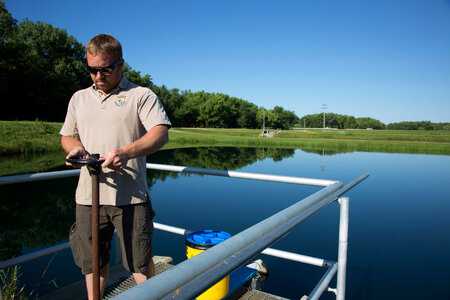 Fishery Biologist adjusts water flow to fish pond photo