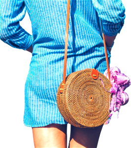 Woman wearing blue and white striped dress with brown rattan crossbody bag near