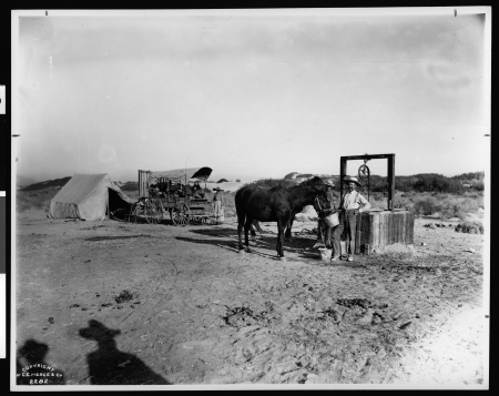 Group of people with a covered wagon and tent at Indian Wells on the Butterfield Stage Line east of Palm Springs and west of Indio, ca.1903-1904 (CHS-2282), Carl Eytel