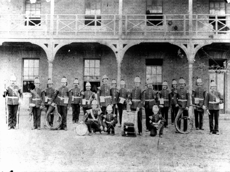 Military band, with their instruments, in front of a brick building (9189469832), circa 1900