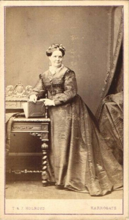 Smiling woman with book by T & J Holroyd, between 1863 and 1872