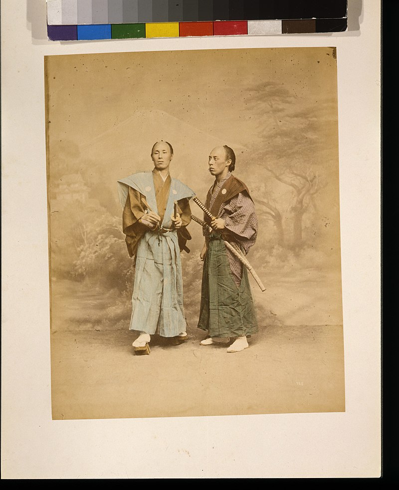 Two Japanese men, possibly samurai, full-length studio portrait with backdrop, standing, one facing front and the other facing left, each with two swords LCCN2009632870, 1877