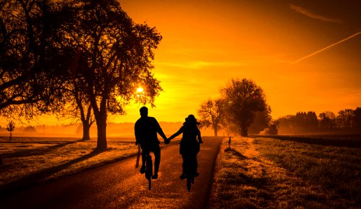 Couple Riding Bicycles into Sunset. Free illustration for personal and commercial use.